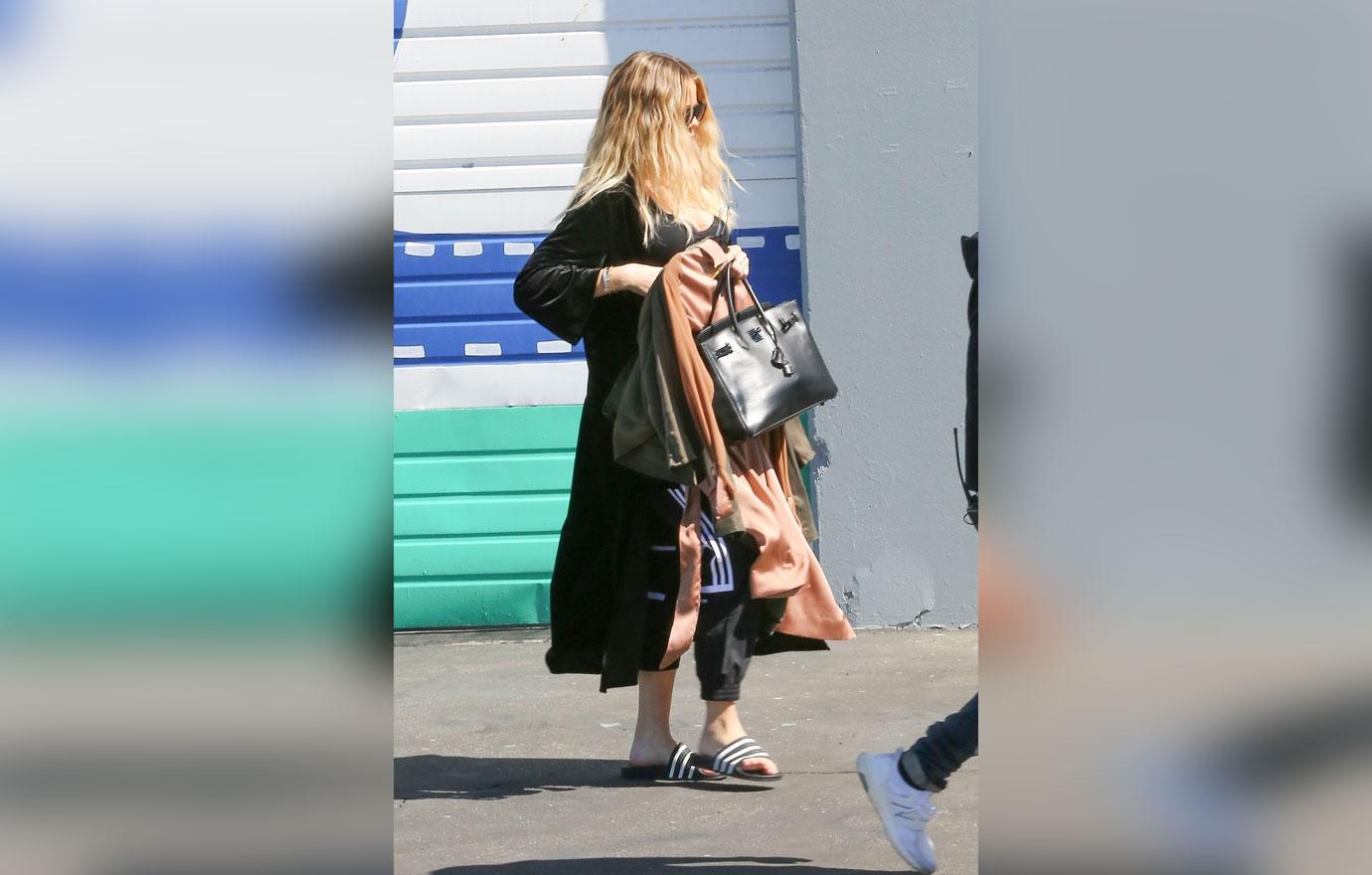 *EXCLUSIVE* Pregnant Khloe Kardashian hides her baby bump while leaving a studio