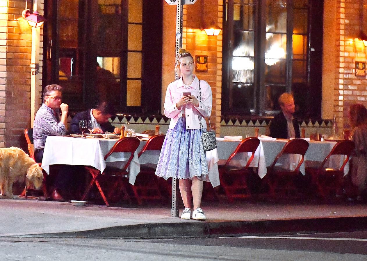 EXCLUSIVE: Elle Fanning sits on a curb and chats with a friend after dinner at Little Dom&#8217;s in Los Feliz, CA.