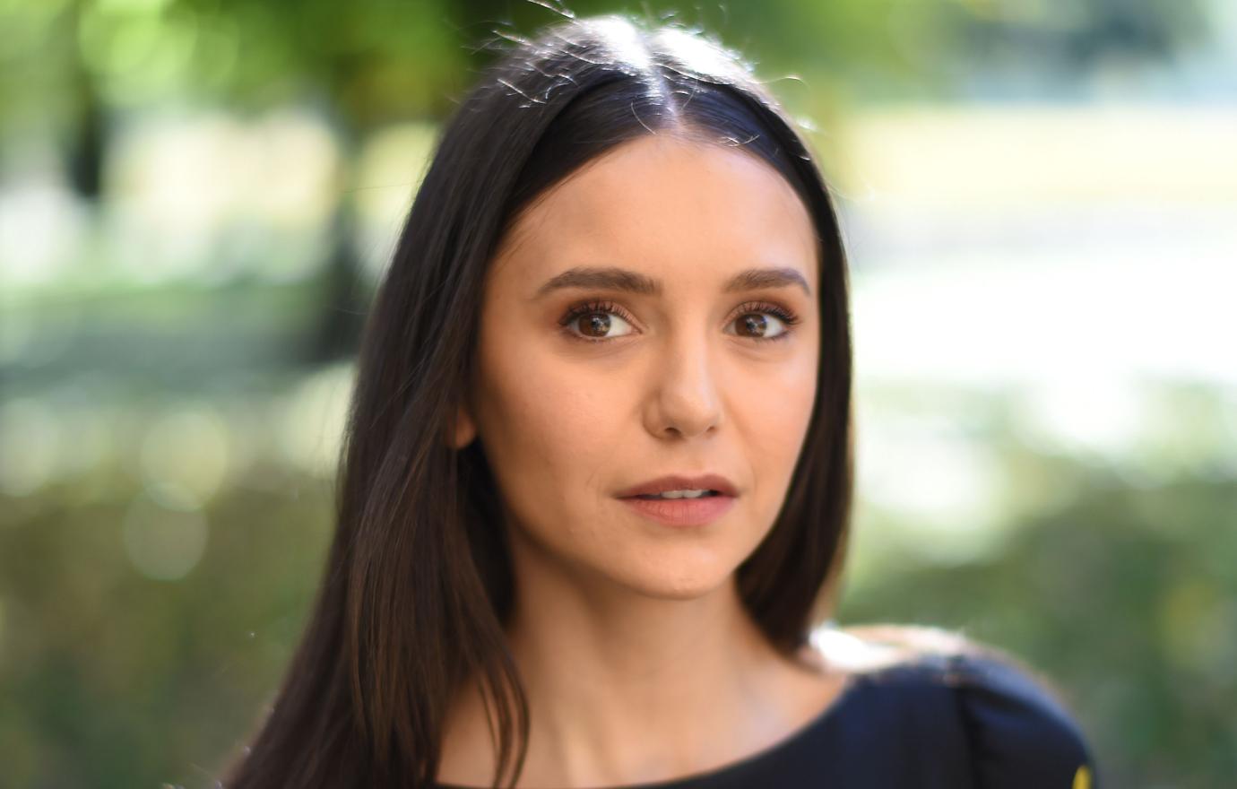 Nina Dobrev wore a black blouse adorned with multi-colored gems.