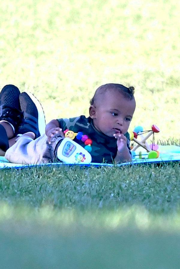 saint west smelling shoe laughing having fun in the park