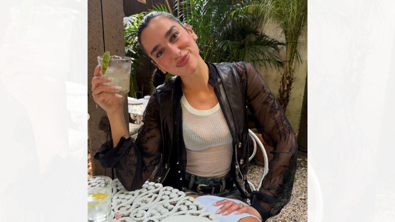 Image of Dua Lipa sipped on a margarita in the see-through shirt.  