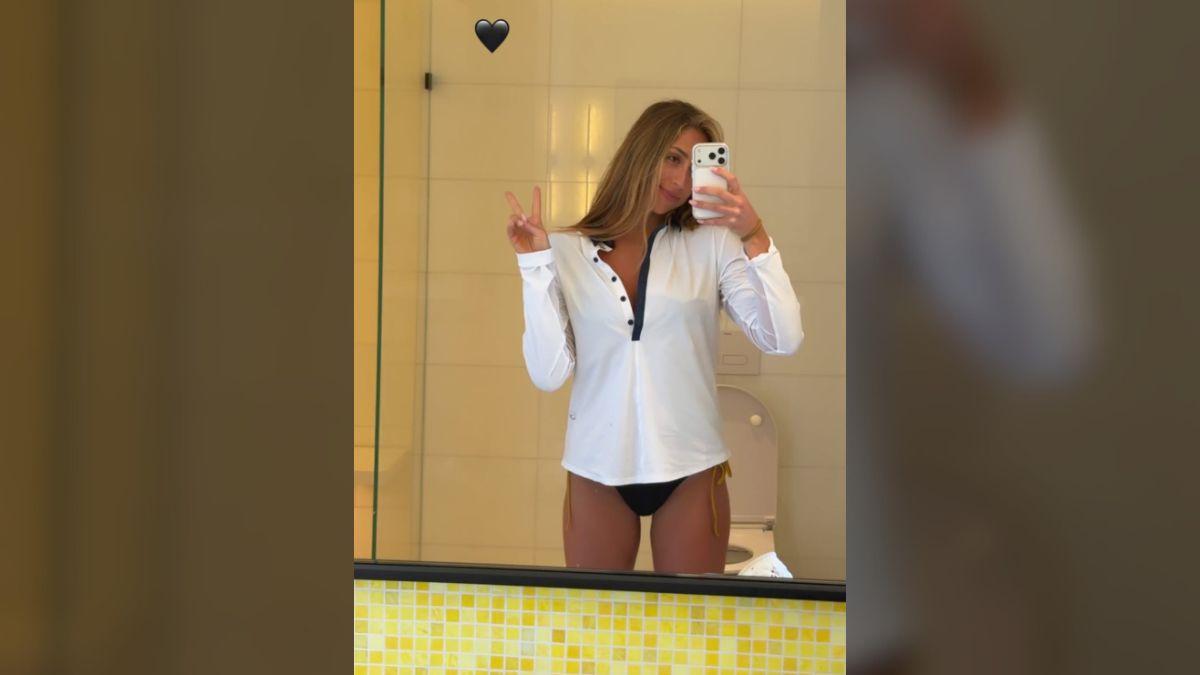 Photo of Tate McRae layered a white long-sleeve top over her bikini in a new mirror selfie.