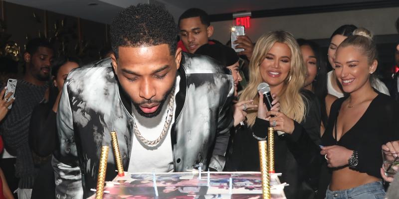 Tristan Thompson blows out candles on his birthday cake as Khloe Kardashian and others look on. Tristan is currently famous for being one of the most talked about cheating celebrities of 2018