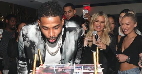 Tristan Thompson blows out candles on his birthday cake as Khloe Kardashian and others look on. Tristan is currently famous for being one of the most talked about cheating celebrities of 2018