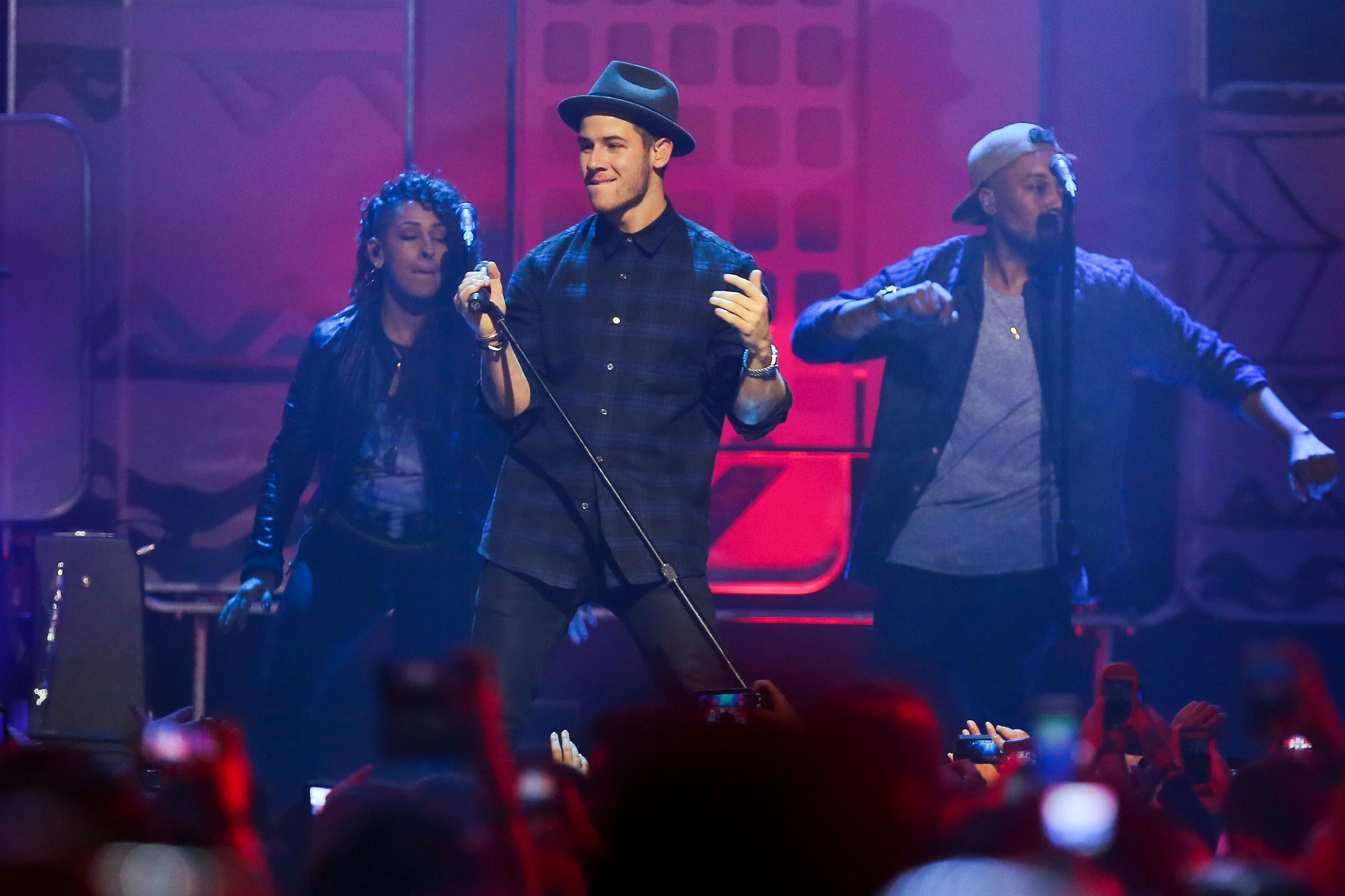 Nick Jonas wears flannel and a fedora during a concert performance for We Day Vancouver