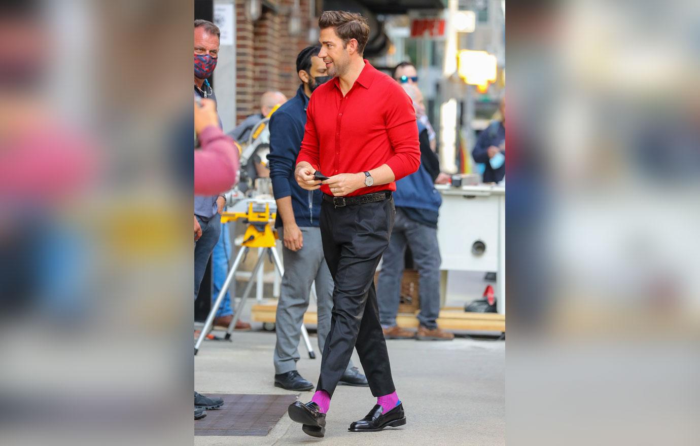 john krasinski seen wearing a red shirt and a purple socks while arrives at the late show with stephen colbert ok