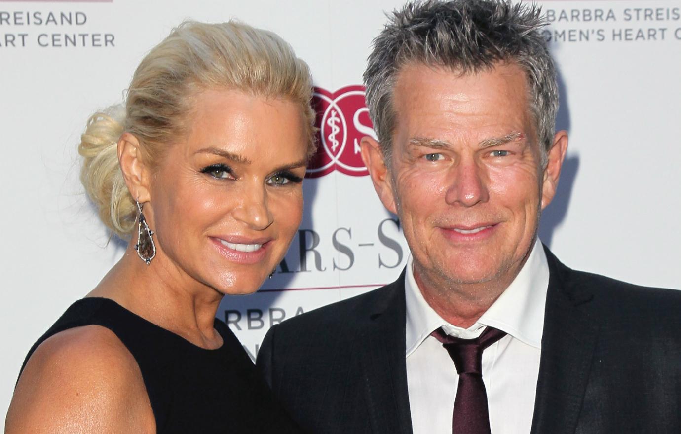 Yolanda Hadid wears a black dress and her hair in an updo alongside then-husband David Foster, wearing a black jacket and tie at a benefit dinner.