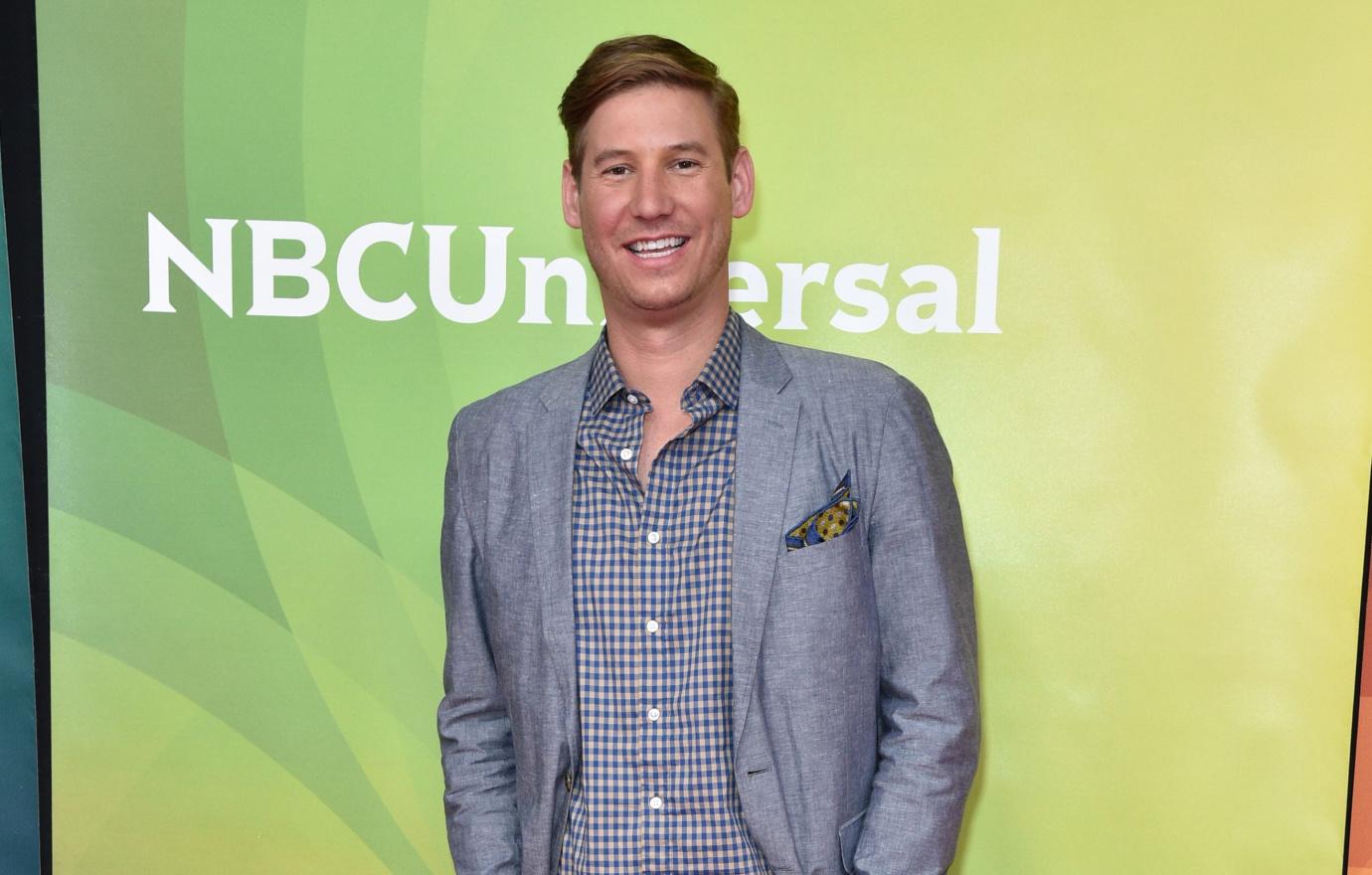 Southern Charm star Austen Kroll smiles for the camera in a gray blazer