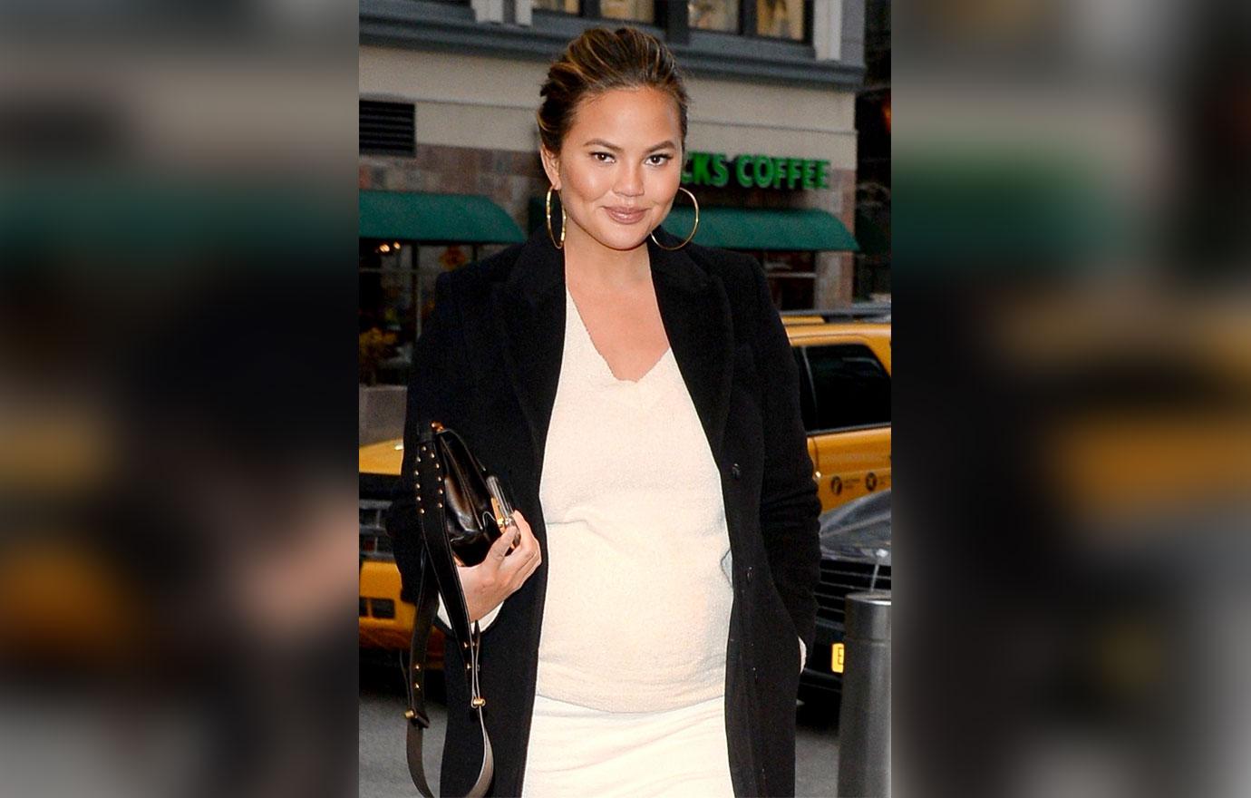 Chrissy Teigen shows off her baby bump in a white form fitted dress