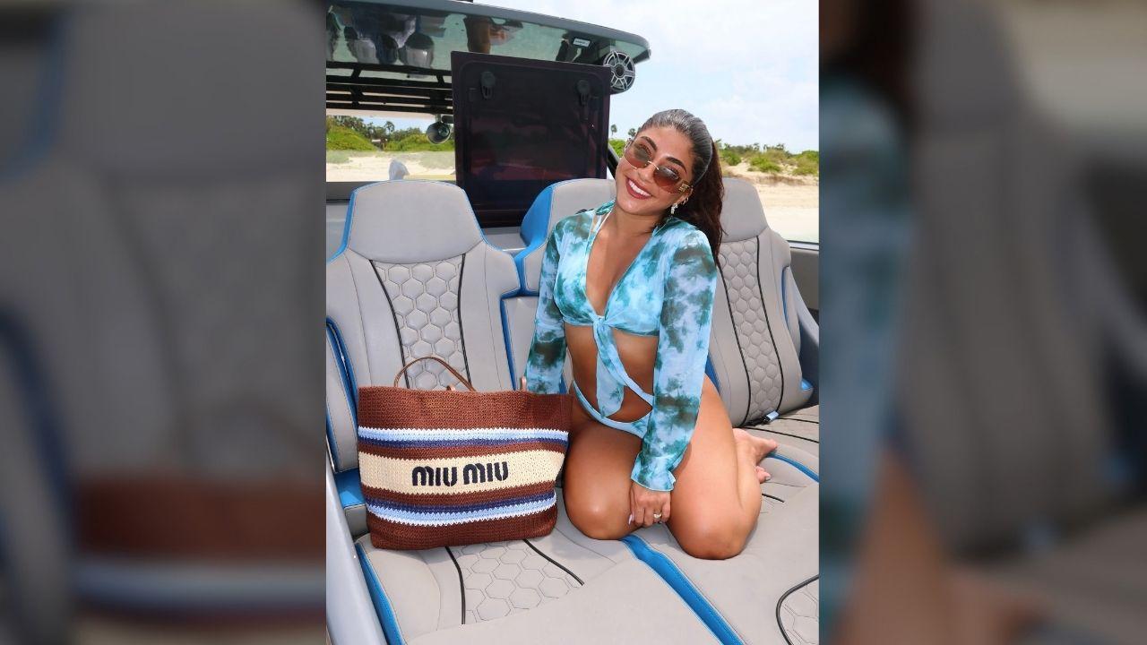 Photo of Milania Giudice posed on the beach with a new Miu Miu bag.