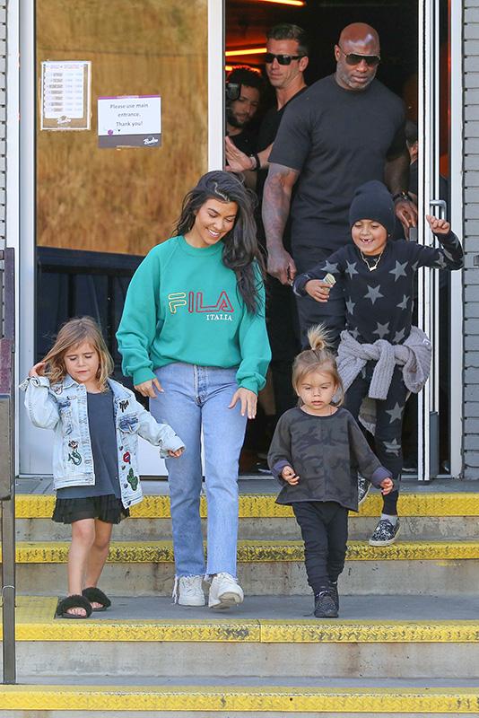 Kourtney Kardashian grins from ear to ear as she leaves the bowling alley with her family