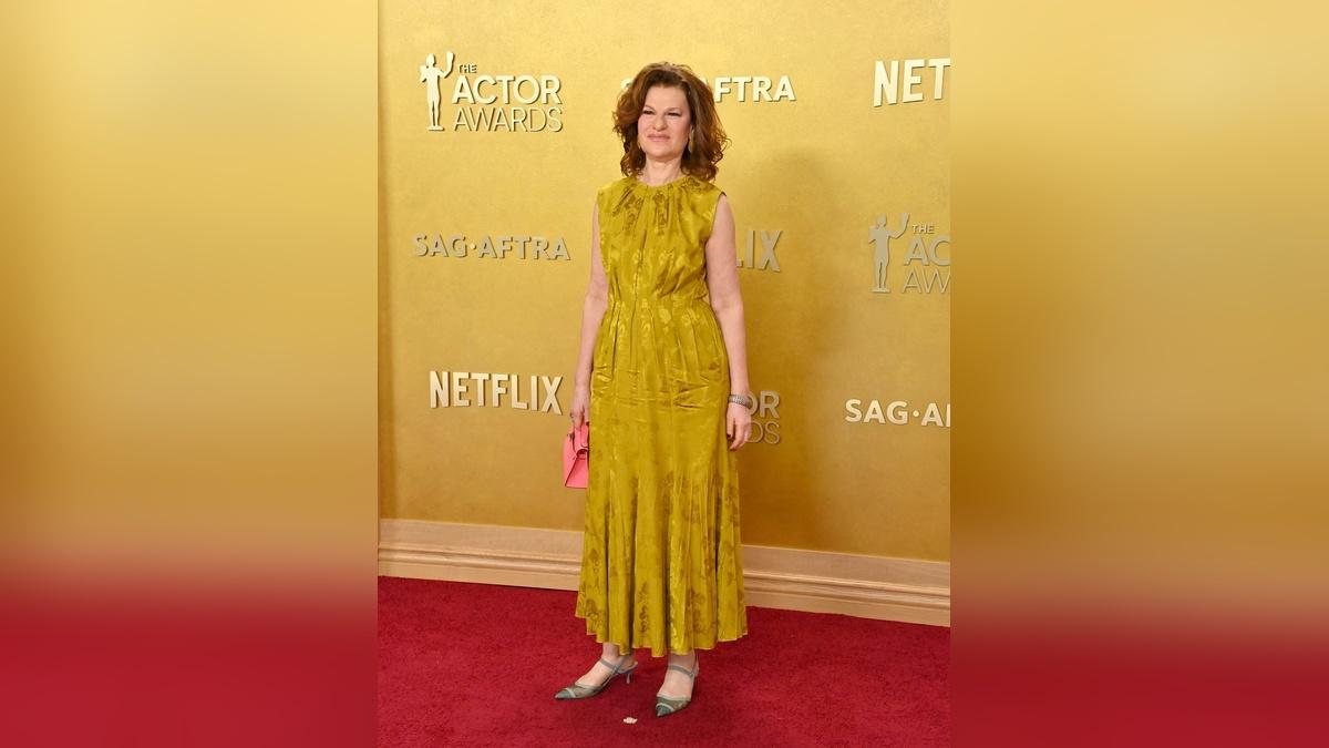 Image of Sandra Bernhard drowned in a mustard-yellow maxi.