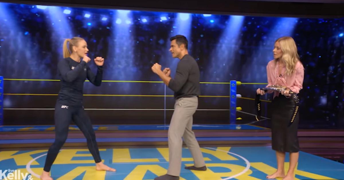Image of Kelly Ripa stood to the side as UFC champion Valentina Shevchenko taught Mark Consuelos how to fight.