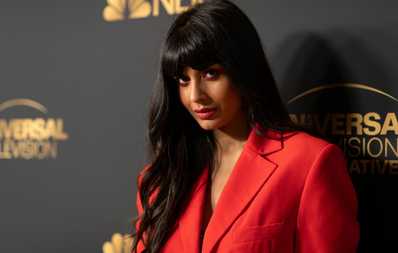 Jameela Jamil in a red jacket on the red carpet.