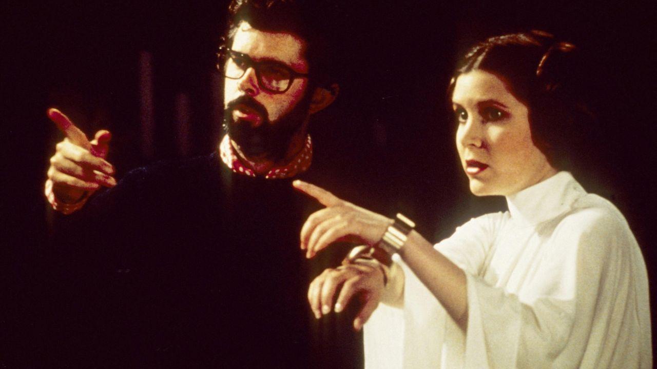 Image of George Lucas and Carrie Fisher as she plays Princess Leia.