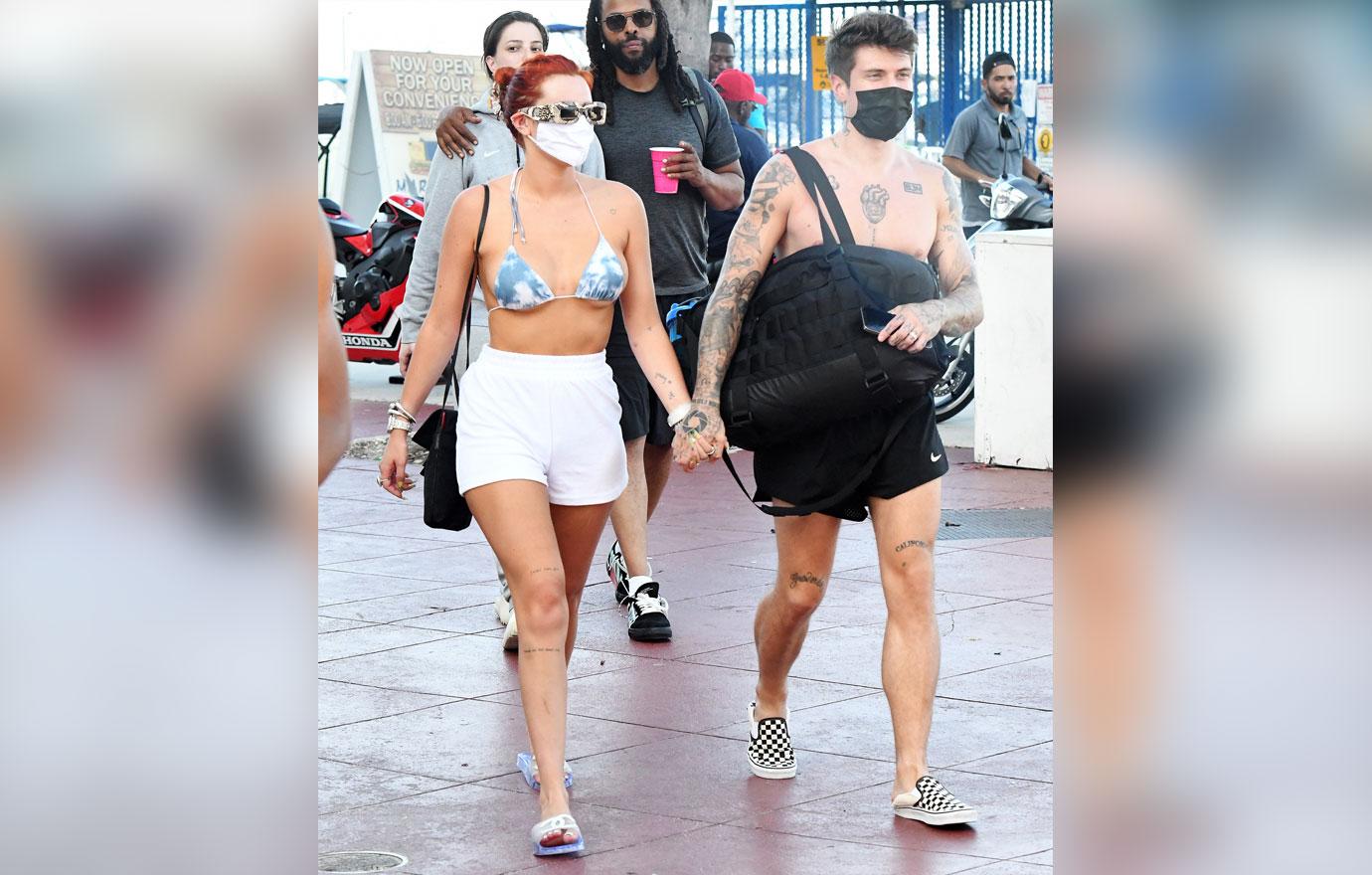 bella thorne wears a blue and white bikini as she holds hands with fiance benjamin mascolo while getting off a yacht