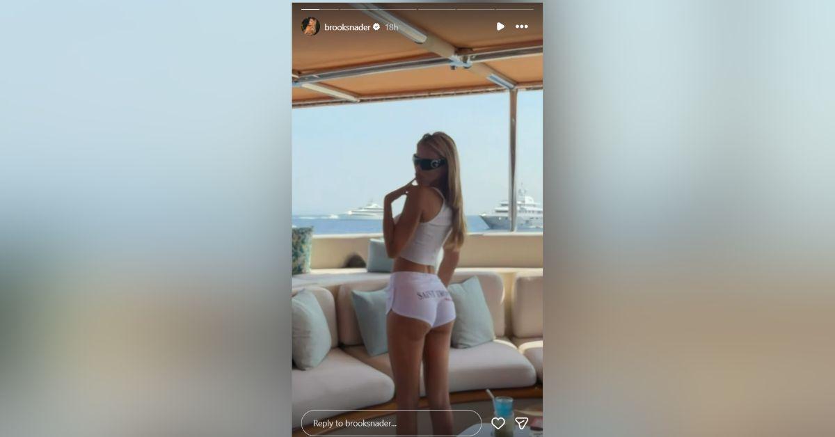 image of Brooks Nader shared a yacht photo wearing ultra-short white shorts and a fitted tank top while enjoying a luxurious summer getaway.