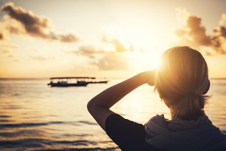 young woman watching sunrise at Pwani Mchangani beach (Zanzibar, Tanzania, Africa).