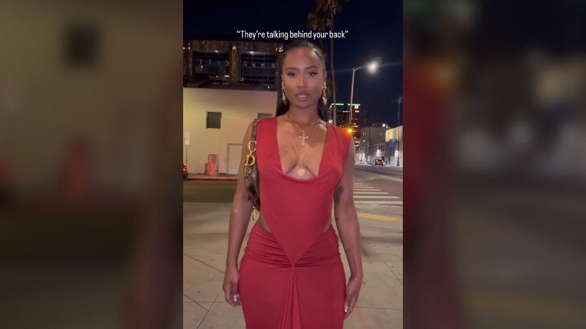 Photo of Kayla Nicole posed in a curve-hugging red dress while addressing people talking behind her 'back.'
