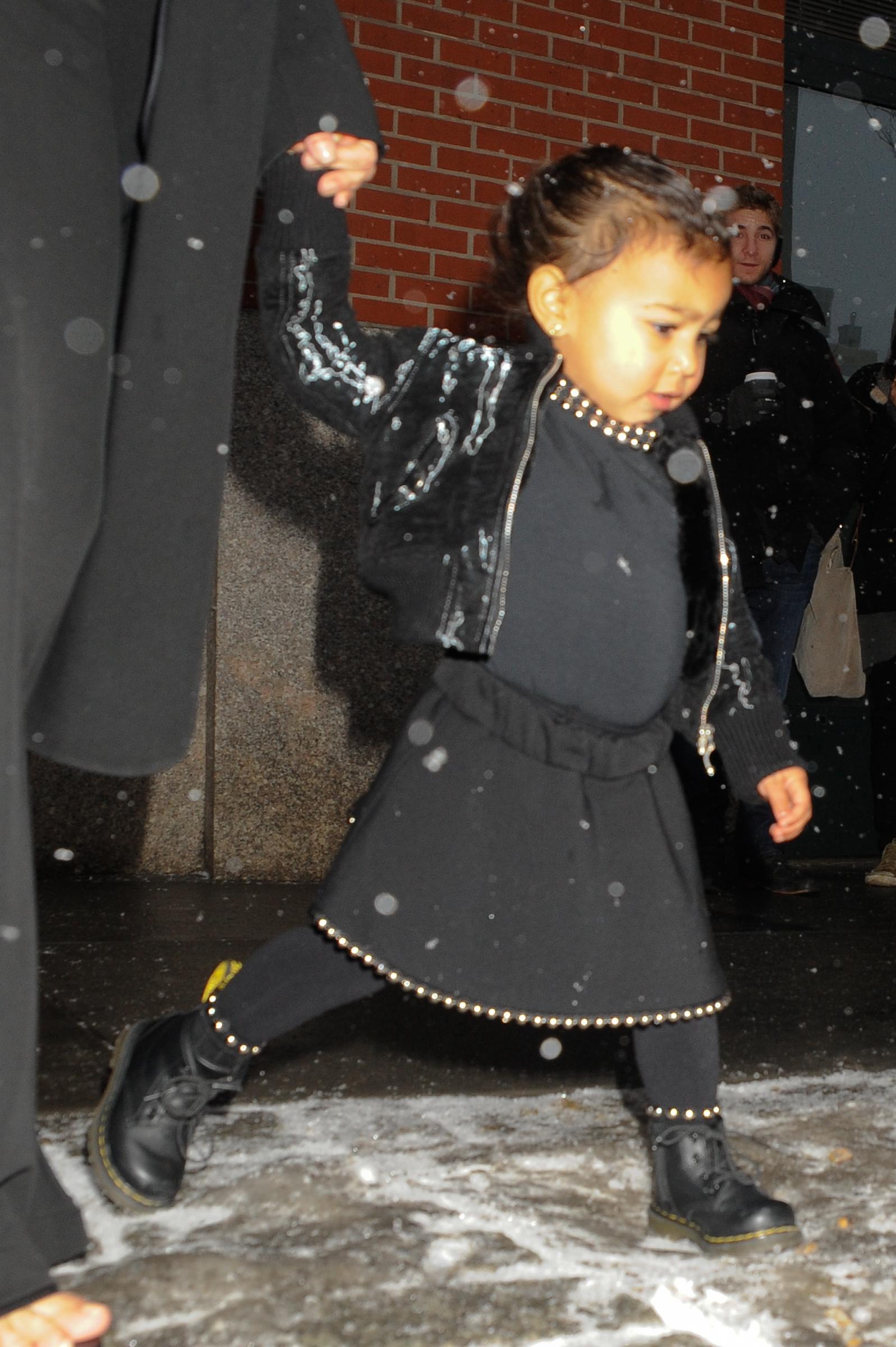 North West walks, held by her mom Kim Kardashian, on their way to New York Fashion Week