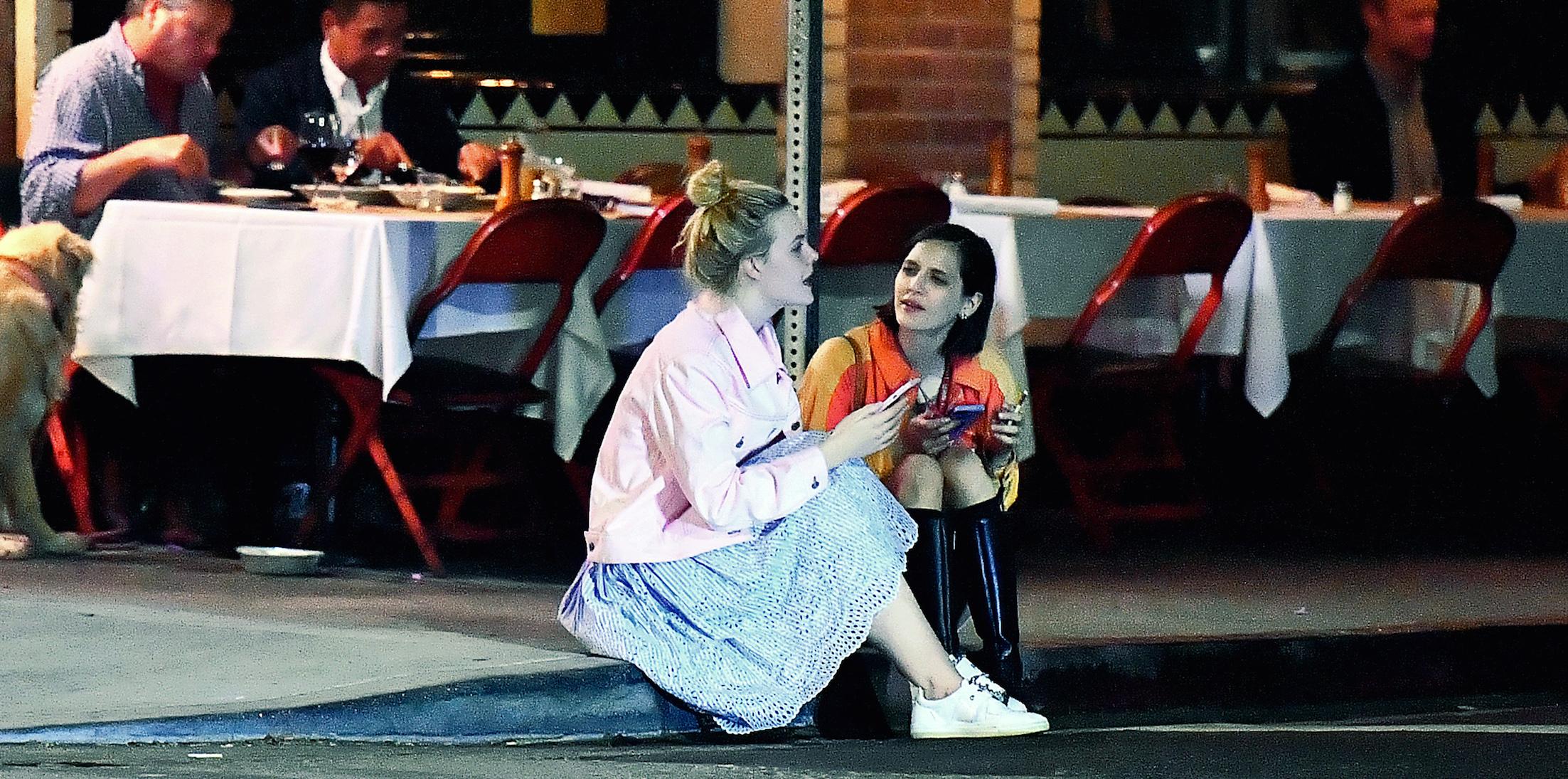 EXCLUSIVE: Elle Fanning sits on a curb and chats with a friend after dinner at Little Dom&#8217;s in Los Feliz, CA.