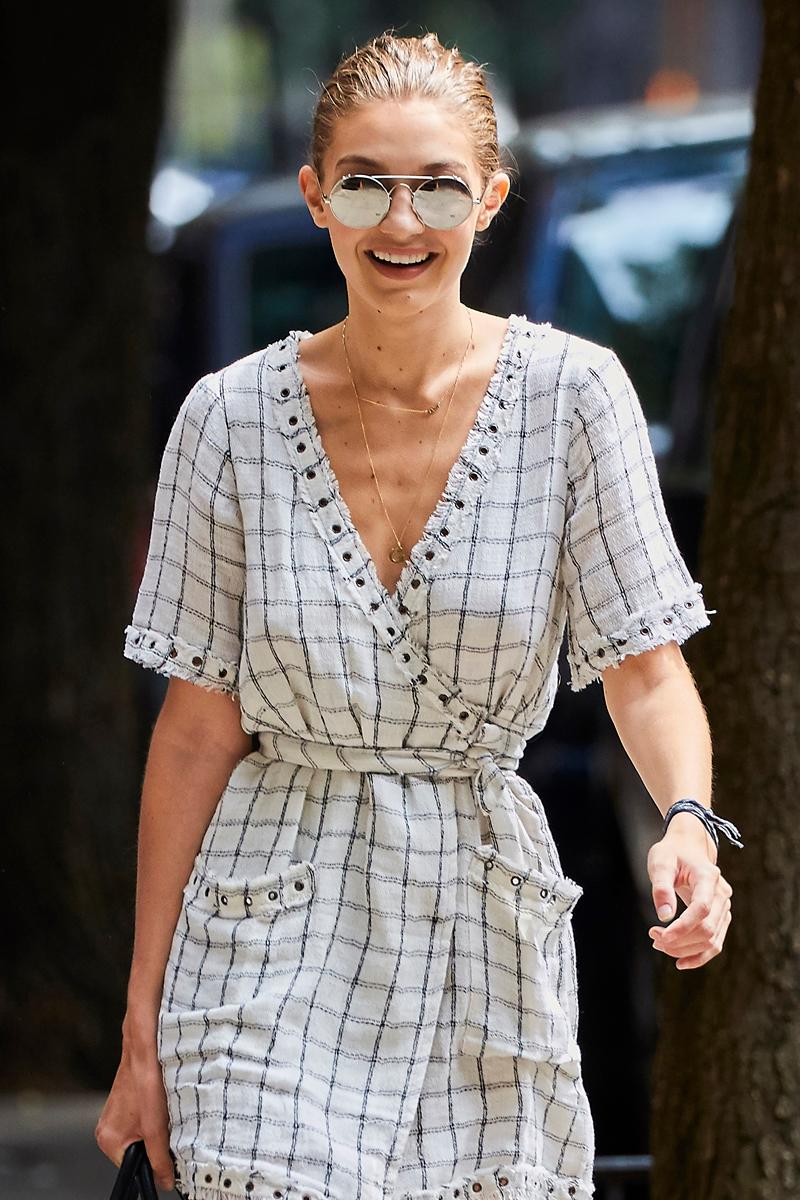 Gigi Hadid is all smiles while wearing a white tunic top in NYC