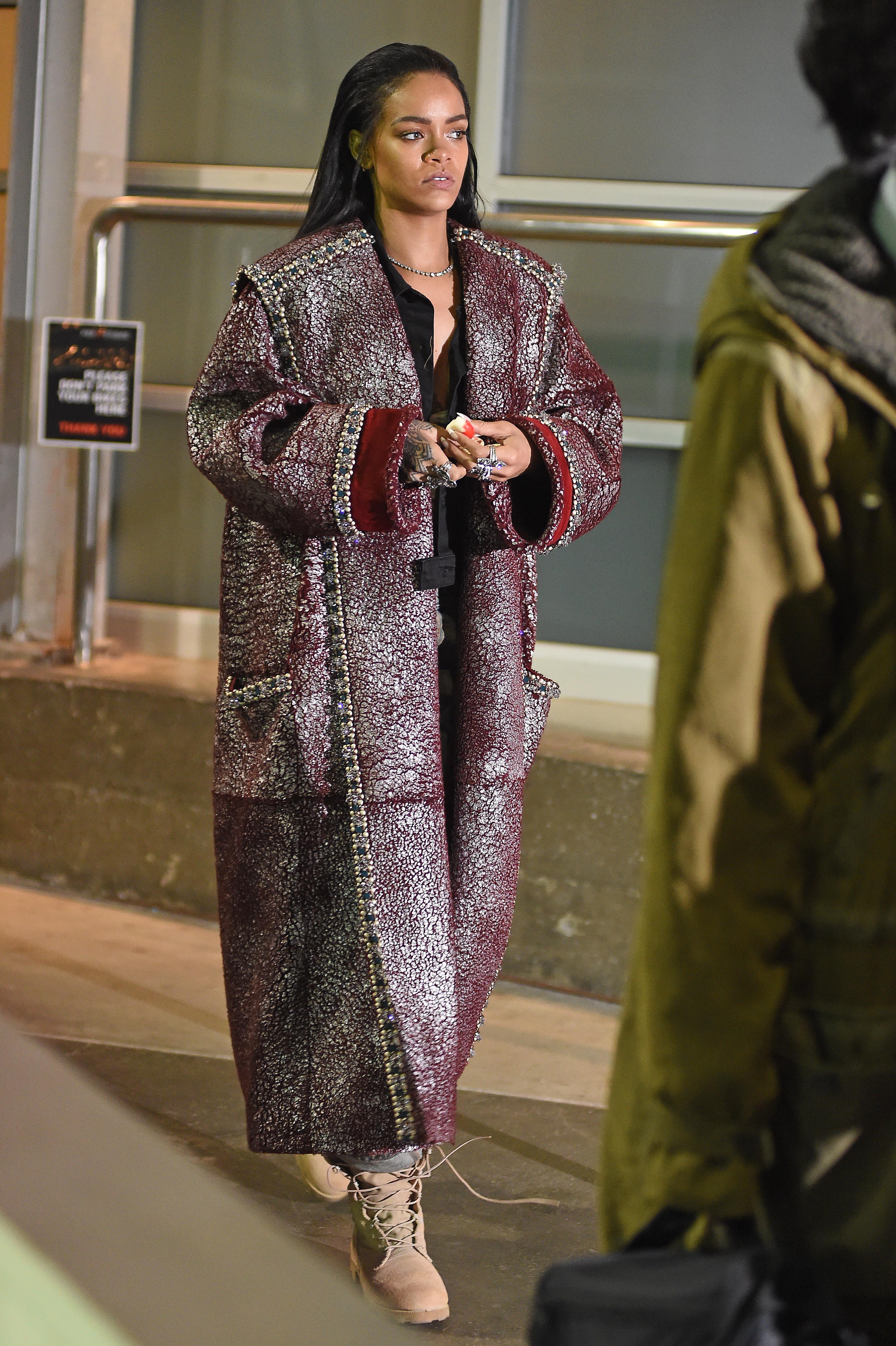 Rihanna is seen out in a purple trench coat as she stops by the studio for photo shoot in Chelsea, NYC