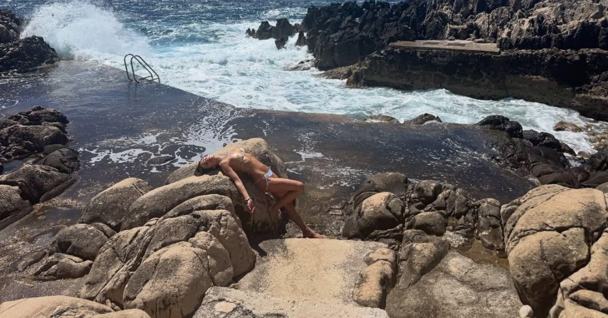 image of The actress posed on rocky cliffs beside crystal-clear water while soaking up the sunshine in a colorful string bikini.
