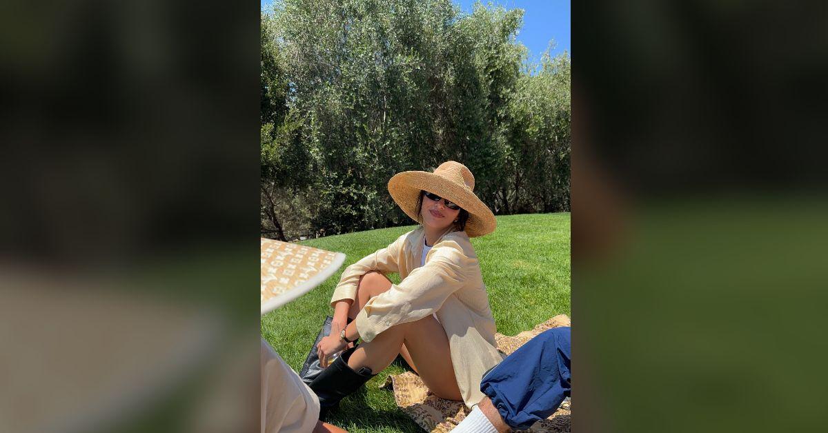 Image of Kendall Jenner shaded her eyes from the sun in a large hat.