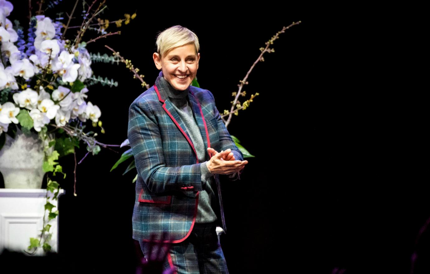 Ellen on stage in a blue check jacket.