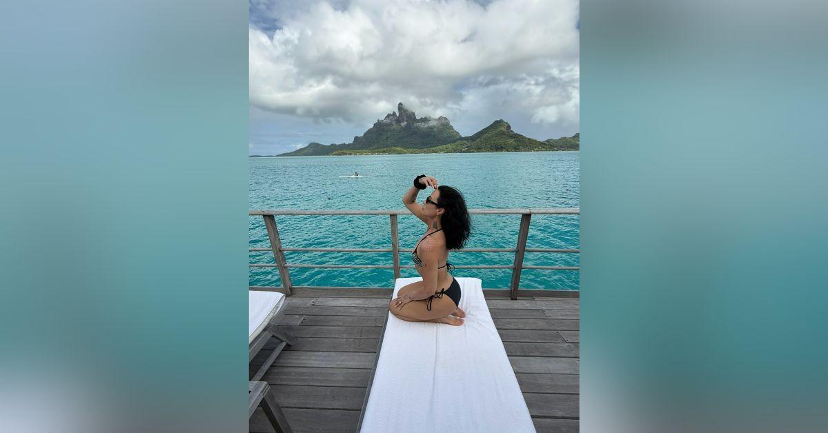 Image of Demi Lovato lounged by the ocean in a skimpy swimsuit.