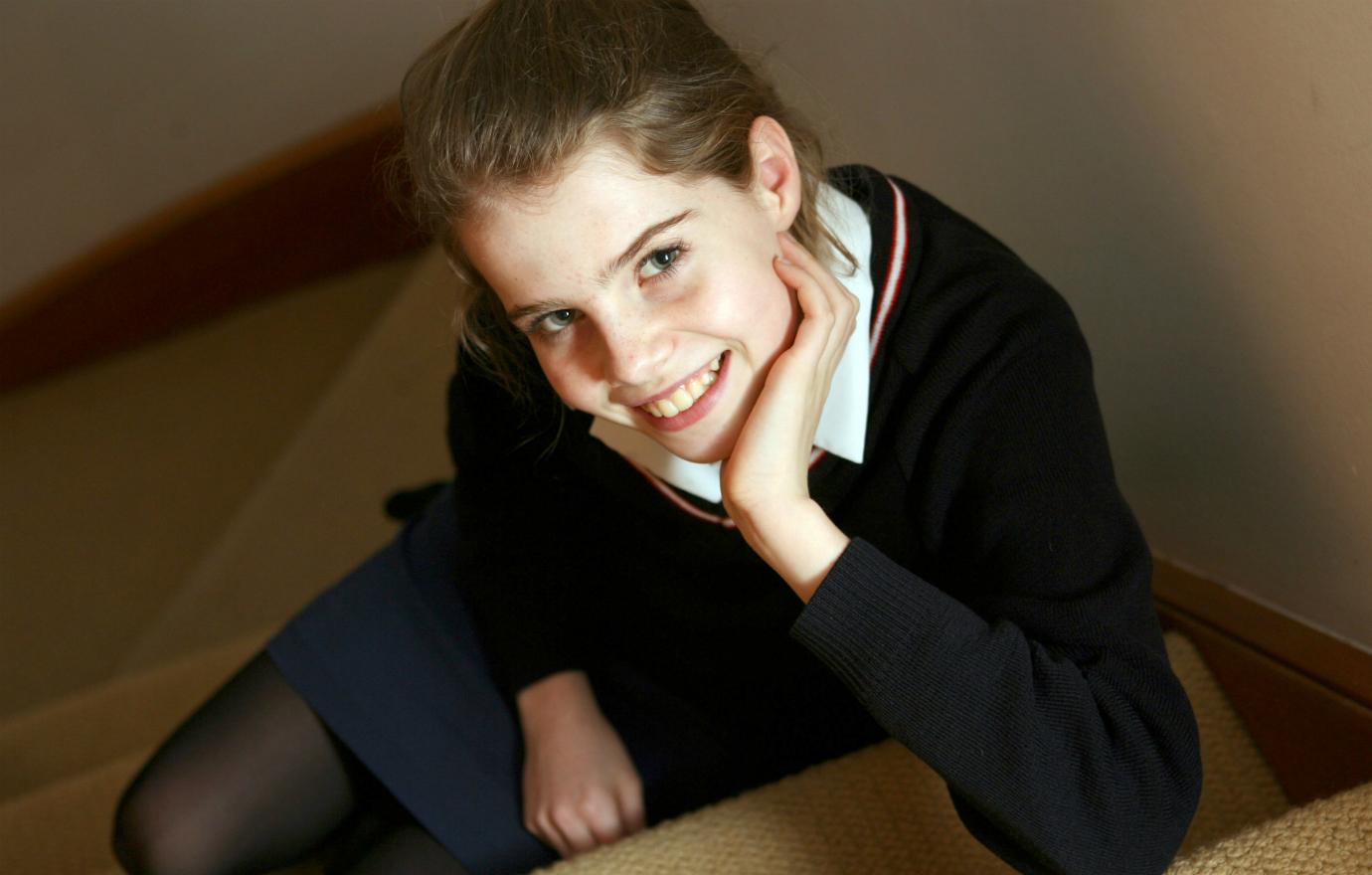 12 year old Lucy Boynton wears a school uniform and poses for the camera.