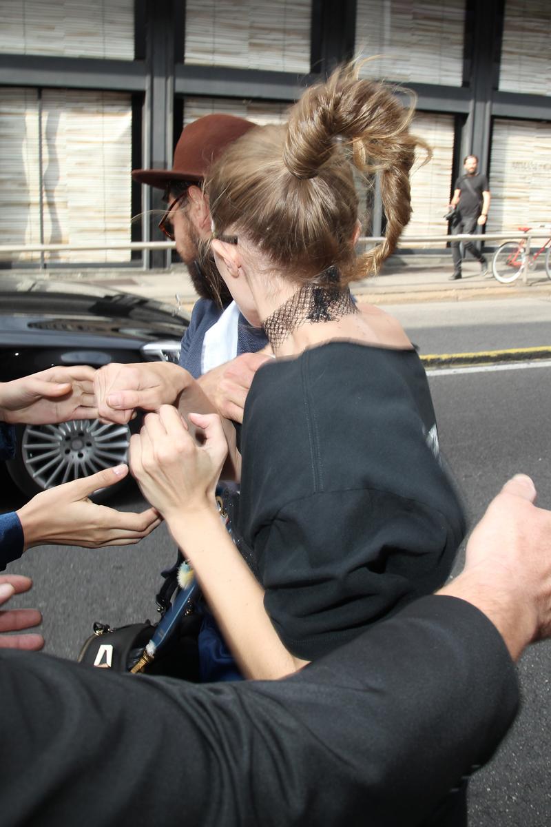 Gigi Hadid gets lifted up by a prankster fan as she leaves the Max Mara fashion show