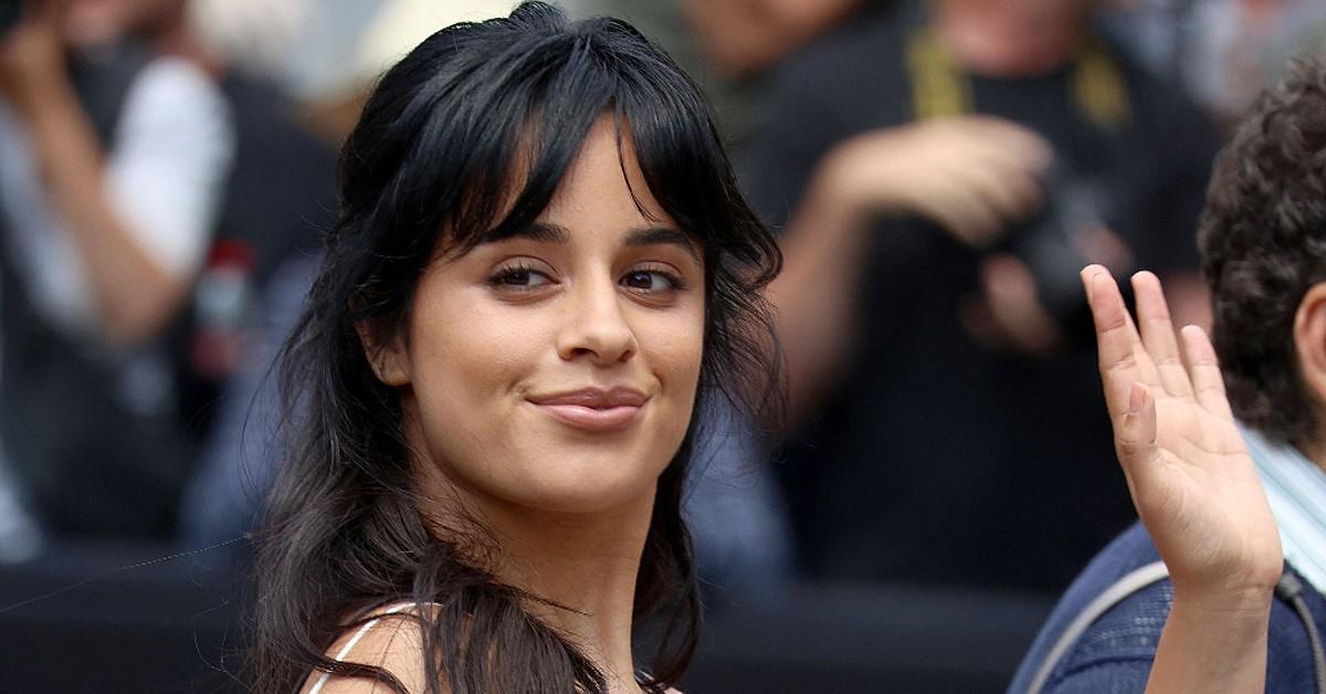 Camila Cabello wears an orange crop top and shorts during a
