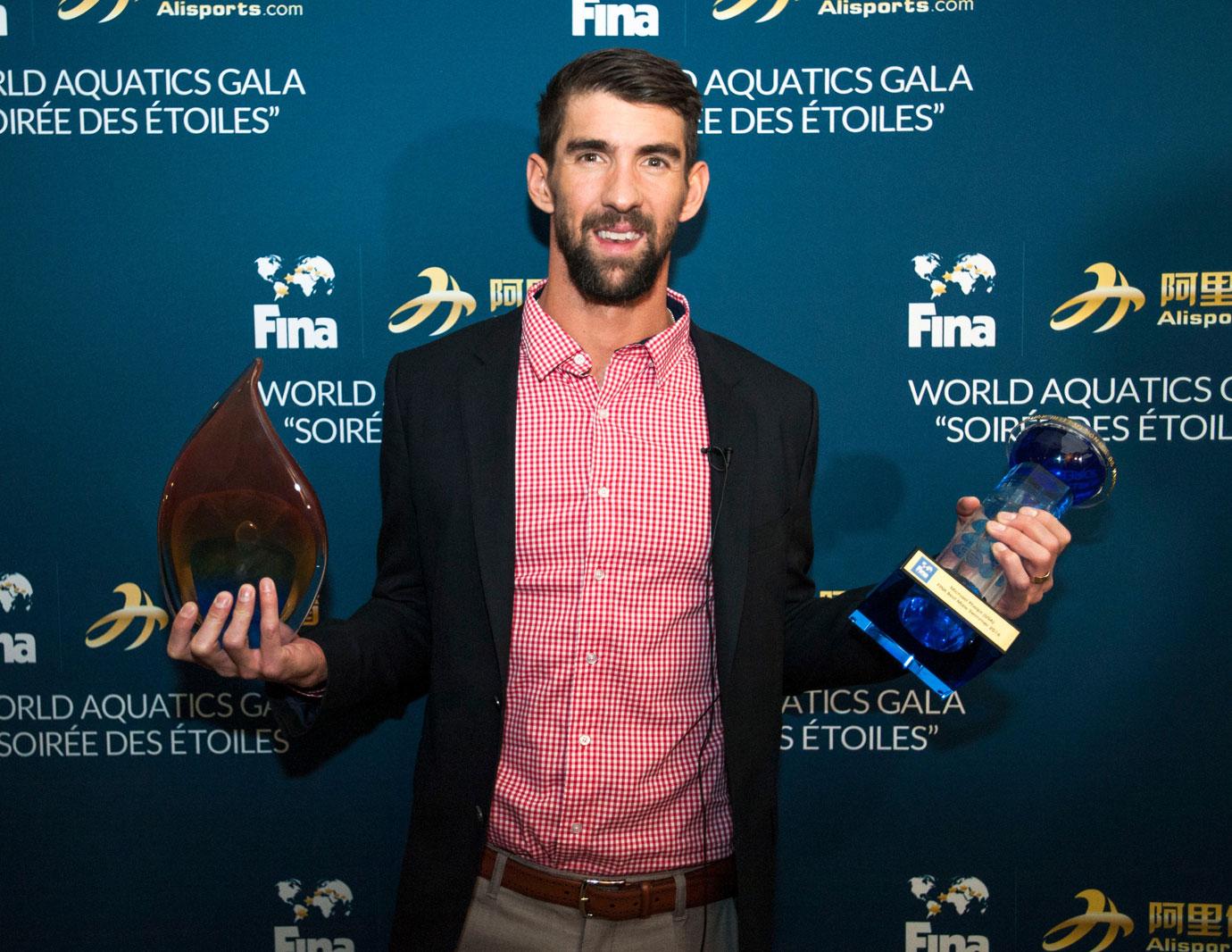 michael phelps holding up two awards