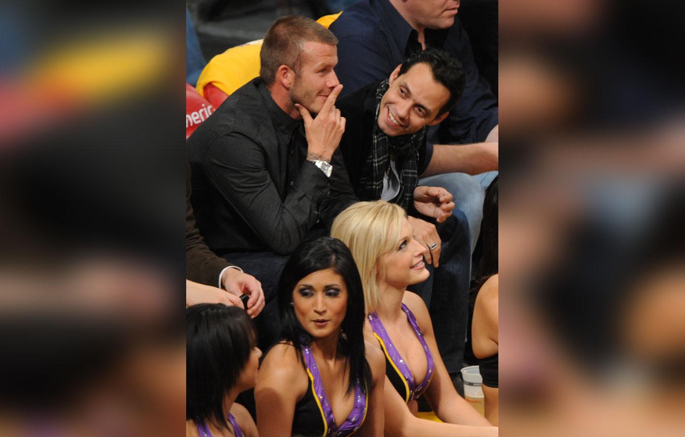 Soccer player David Beckham (L) and singer Marc Anthony (R) sit courtside