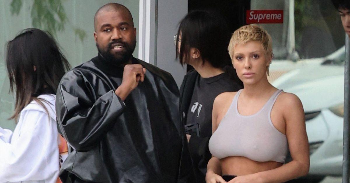 image of Kanye West stood by the model in a leather jacket.