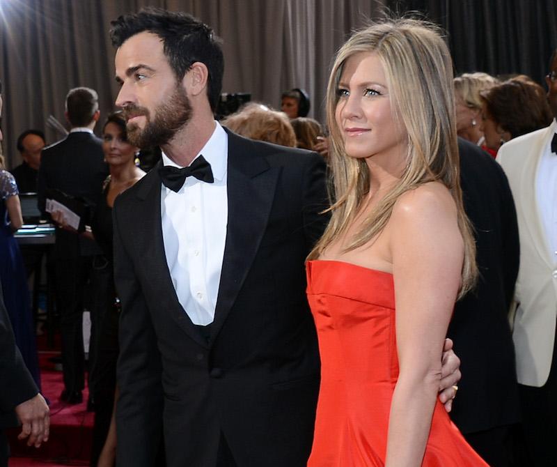 woman in red dress and man in suit at the Oscars