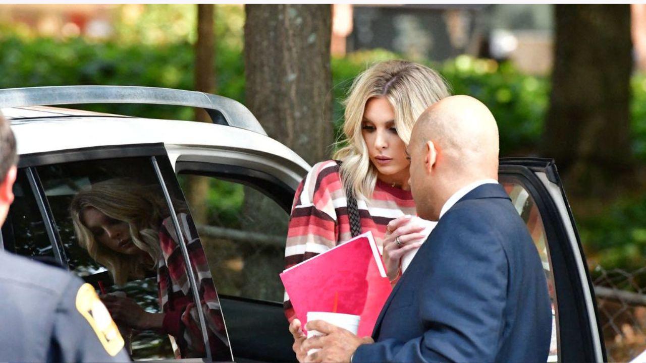Image of Chrisley getting out of a car with her lawyer and a police office waiting.