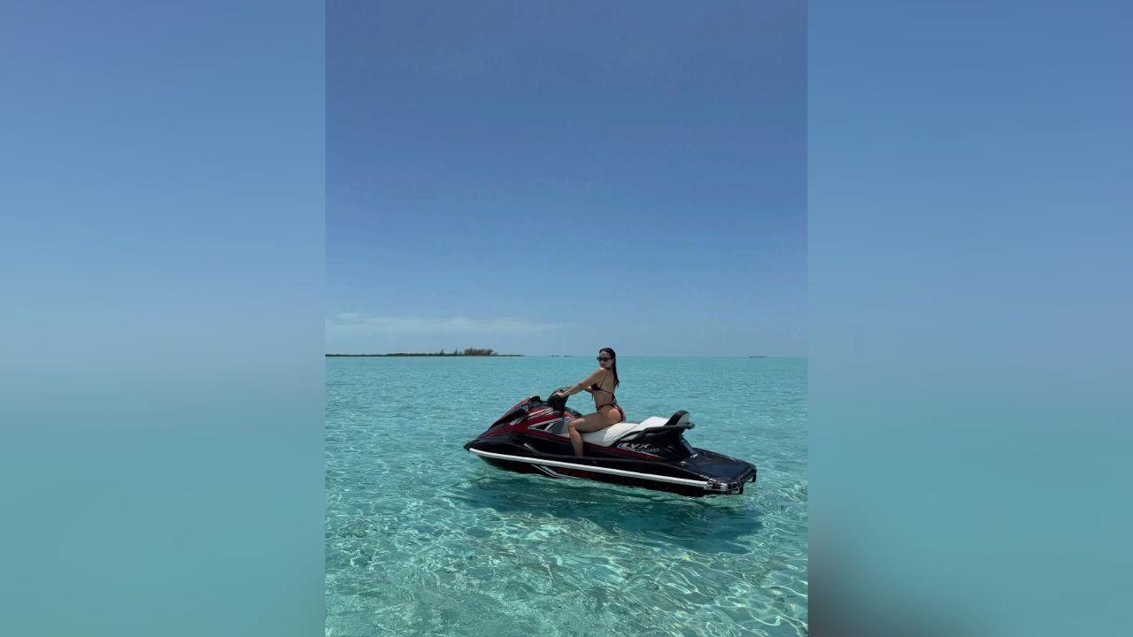 image of Demi Lovato posed on a jet ski wearing a red-and-black printed bikini and dark sunglasses.