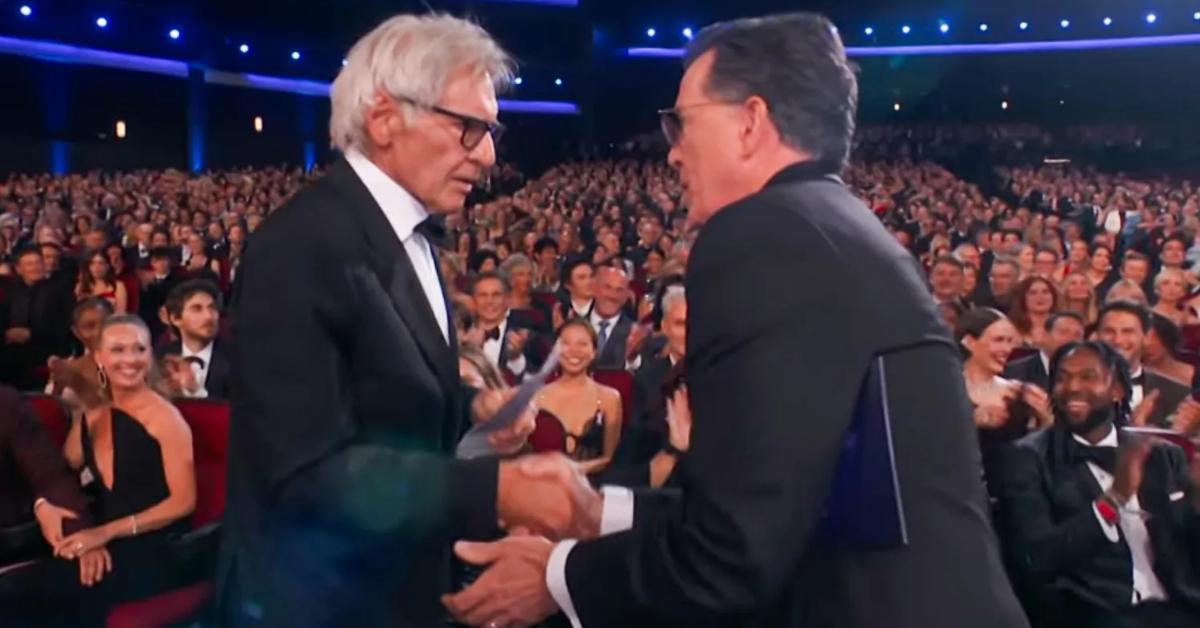 Image of Stephen Colbert jokingly handed his resume to Harrison Ford at the 2025 Emmy Awards.