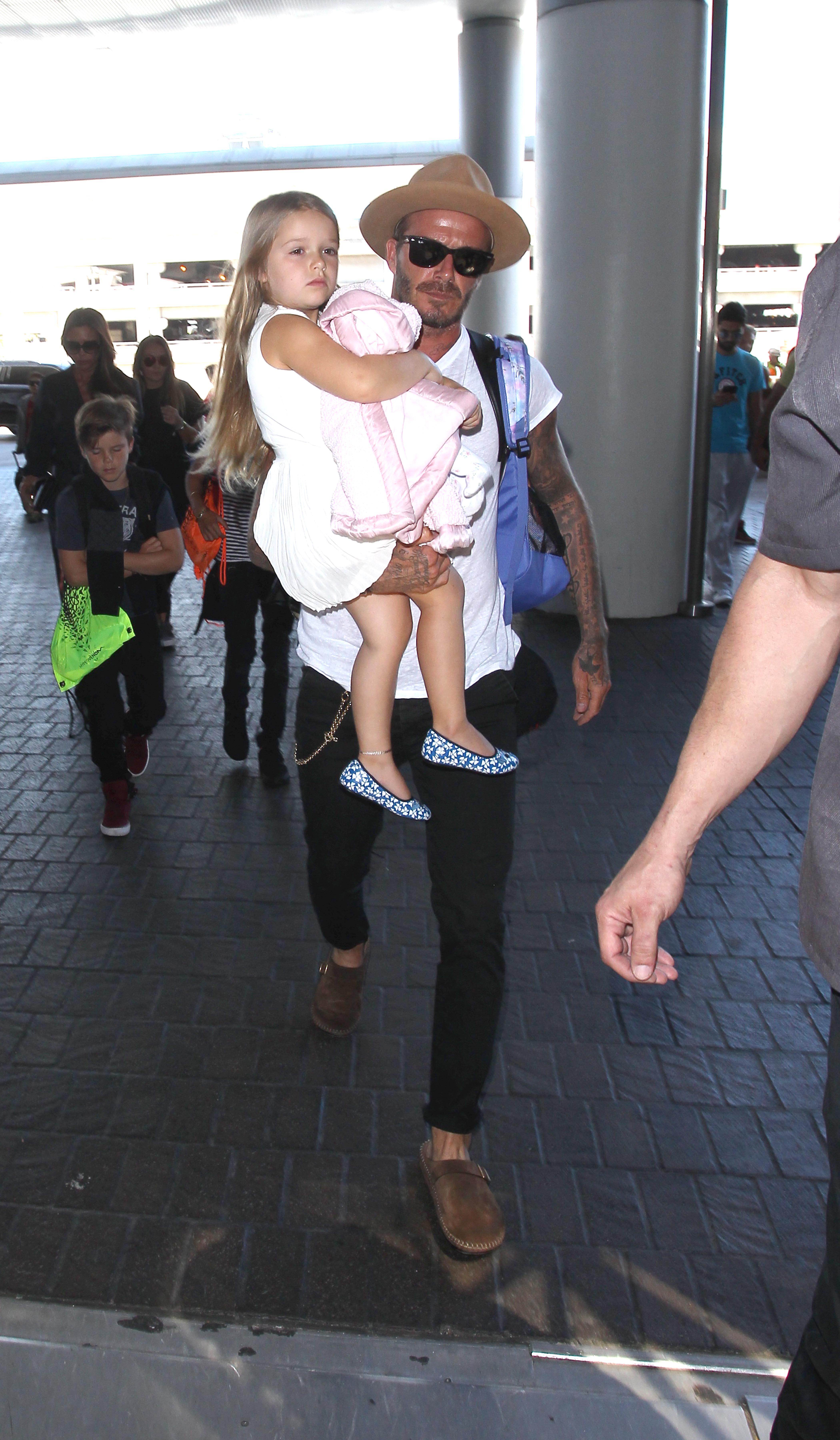 David Beckham carries daughter Harper as he &amp; Victoria arrive at LAX with their sons Brooklyn, Romeo and Cruz