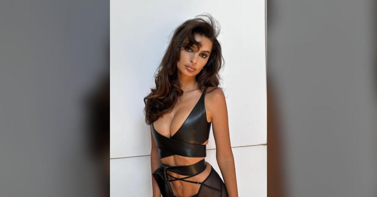 Photo of Emily Ratajkowski posed in a bondage-inspired outfit.