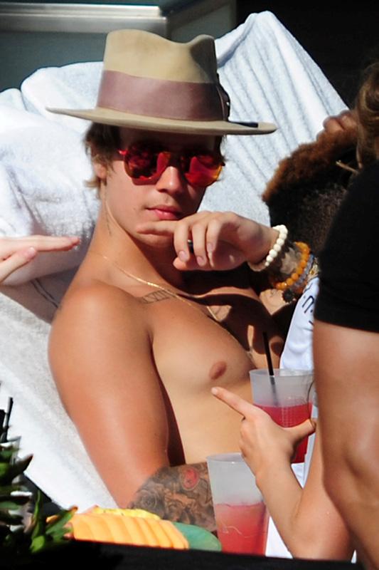 A heavily tattooed Justin Bieber kicks up his feet and relaxes poolside in Miami **USA ONLY**