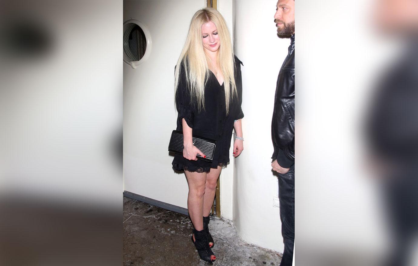 Avril Lavigne oozes gothic glamour in a thigh skimming satin slip dress and sky high boots as she makes a rare appearance at Delilah&#8217;s in West Hollywood