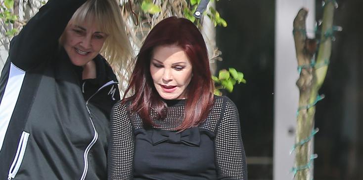 Priscilla Presley is greeted by a mystery man when she arrives at The Wise School in Los Angeles. Priscilla left an hour after arriving carrying a pamphlet with a photo of Elvis Presley, her former husband, on it.